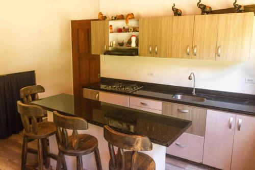 a kitchen with a counter with chairs and a sink at Hermosa CasaQuinta Con Piscina Privada. in Villeta