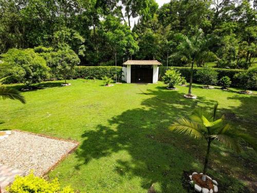 a garden with a small shed in the middle of a yard at Hermosa CasaQuinta Con Piscina Privada. in Villeta