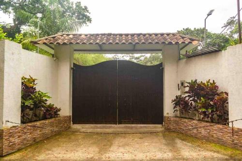 a black garage door on a white house at Hermosa CasaQuinta Con Piscina Privada. in Villeta