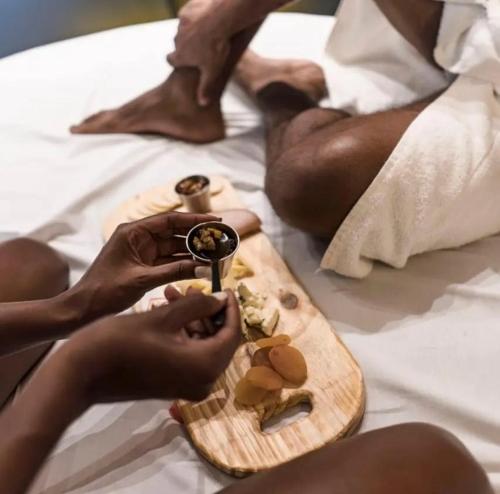 una persona sentada en una cama comiendo comida en una tabla de cortar en Yolo Motel en Brasilia