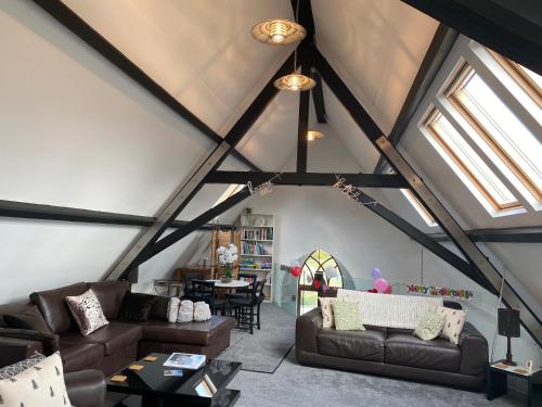a living room with two couches and a table at Converted chapel - Sant Pedr Newydd - with sea views in Amlwch