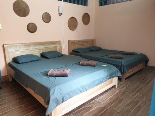 two beds in a room with blue sheets and pillows at Masawi Home in Can Tho