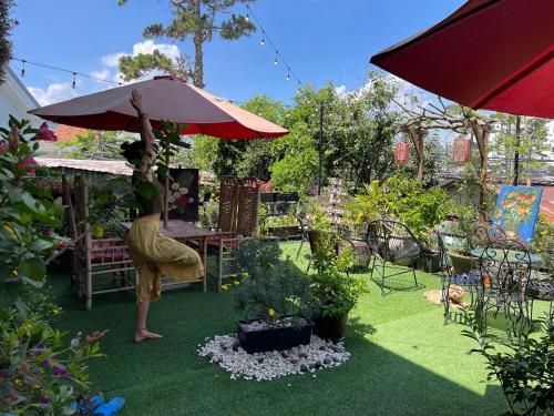 a person standing under an umbrella in a garden at Redhouse Dalat Hotel in Da Lat