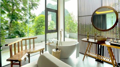 a bathroom with a tub and a table and a mirror at Minawa Kenhga Resort & Spa Ninh Binh in Ninh Binh