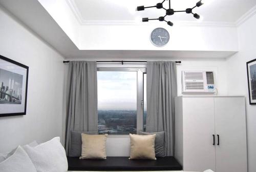 Habitación con ventana y sofá con almohadas en New York Suite III at Avida Towers Aspira, en Cagayan de Oro