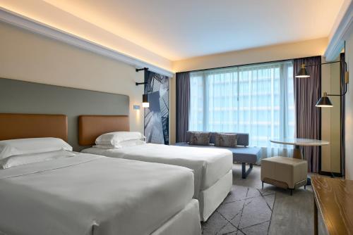 ein Hotelzimmer mit 2 Betten und einem Tisch in der Unterkunft Sheraton Hong Kong Hotel & Towers in Hongkong