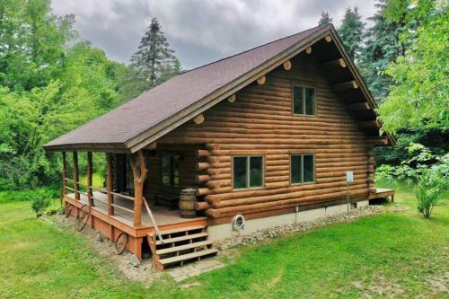 a log cabin with a porch and a roof at Coyote Fire Retreat in Evart
