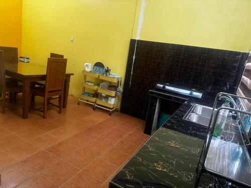 - une cuisine et une salle à manger avec une table et une cuisinière dans l'établissement Sobey Laris Homestay QASEH, à Pasir Mas