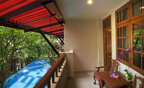 a balcony of a house with a table and a window at Green Garden Hotel in Kuta
