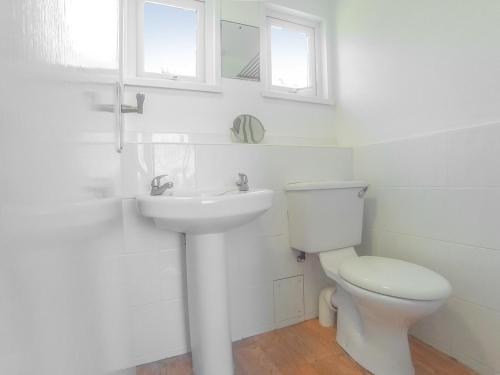 a white bathroom with a toilet and a sink at Chalet 54 in Cromer