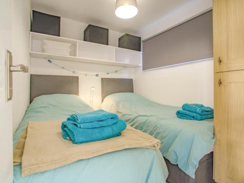 two beds in a room with blue towels on them at Chalet 54 in Cromer