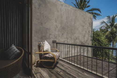 a wicker chair sitting on a balcony with the ocean at The Tiing Tejakula Villas in Tejakula