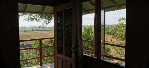 uma porta aberta com vista para um campo em Lake Paradise Cabana em Tissamaharama