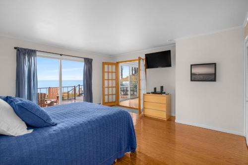 a bedroom with a blue bed and a balcony at Lakefront House with Private Beach by Michigan Waterfront Luxury Properties in Norton Shores