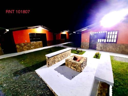 una panchina di pietra di fronte a una casa di notte di El Bambu a Santa Rosa de Cabal