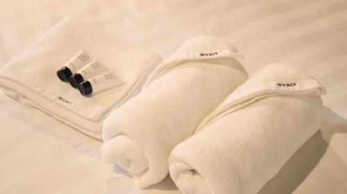 two white towels sitting on a bed with a thermometer at Room V at Kluang Parade Near Bus Stop Kluang in Kluang