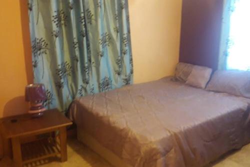 a bedroom with a bed and a table and a window at Spacious Home in Couva