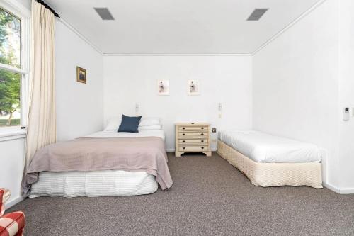 a white bedroom with two beds and a window at Glen Regan Berrima in Berrima