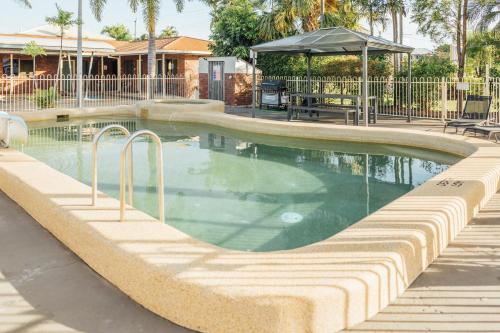 a swimming pool in a resort with a table and chairs at Billabong Lodge Motel in Townsville