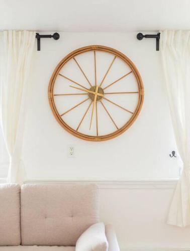 a large clock on a wall above a couch at Cozy getaway - 5 min drive to beach in Cape May