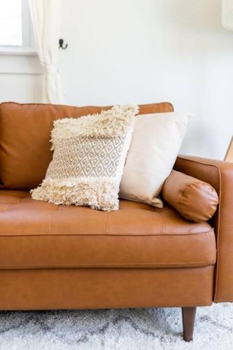 a brown couch with a white pillow on it at Cozy getaway - 5 min drive to beach in Cape May