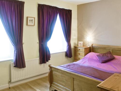 スキップトンにある6 Craven Terraceのベッドルーム1室(ベッド1台付)、紫色のカーテン付きの窓が備わります。