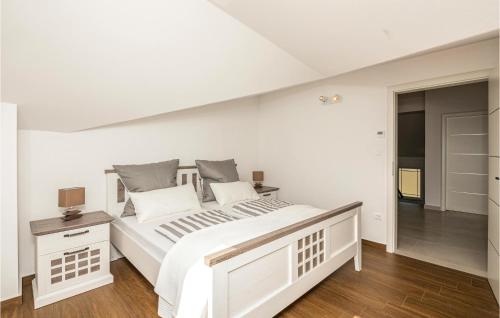 a white bedroom with a large white bed and wooden floors at 4 Bedroom Awesome Home In Kosute in Košute
