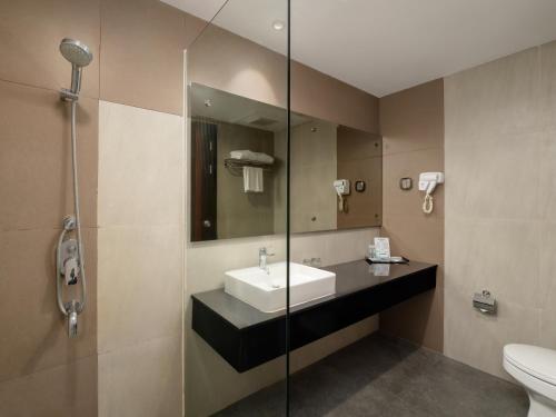 uma casa de banho com um lavatório e uma cabina de duche em vidro. em d'primahotel Kualanamu Medan Formerly Prime Plaza Hotel em Medan