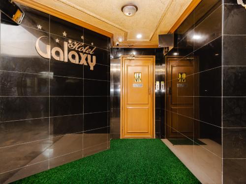a hallway with a yellow door and green carpet at Hotel Galaxy Opp Surat Railway Station in Surat