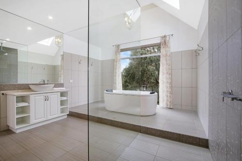 een badkamer met een bad, een wastafel en een raam bij Next to Bliss Luxury Guesthouse in Bright