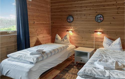 two beds in a room with wooden walls at Awesome Home In Offersy With Sauna, Wifi And 3 Bedrooms in Offersøy
