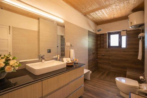 ein Badezimmer mit einem Waschbecken, einem WC und einem Spiegel in der Unterkunft StayVista at Jhelum Kinare in Srinagar