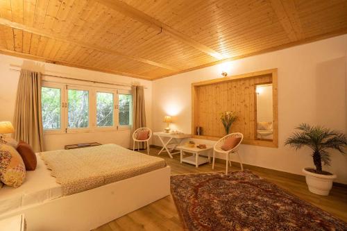 Schlafzimmer mit einem Bett, einem Tisch und Stühlen in der Unterkunft StayVista at Jhelum Kinare in Srinagar