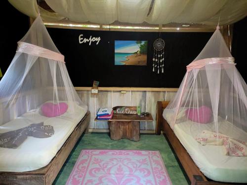 2 camas com redes mosquiteiras num quarto com uma televisão em Jungle Tent 3x3, Latino Glamping & Tours, Paquera em Paquera