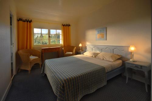 a bedroom with a bed and two chairs and a window at Gîtes de La Ferme De Kereven in Bénodet