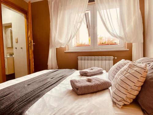 a bed with two pillows on it with a window at Cerla Korbielów in Korbielów