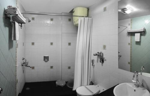 y baño con ducha, aseo y lavamanos. en Honeymoon Inn Mussoorie, en Mussoorie