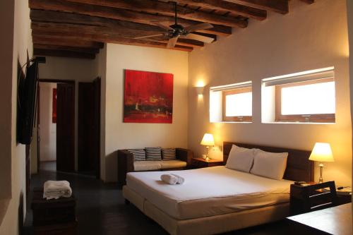 a bedroom with a bed and a chair and two windows at Casa Gaitana - Alma Hotels in Santa Marta