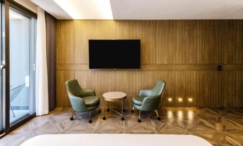 a hotel room with two chairs and a television on a wall at Anseong Nomad Hotel in Anseong