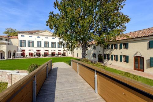 a wooden walkway leading to a building with a tree at Hotel Villa Barbarich Venice Mestre in Mestre
