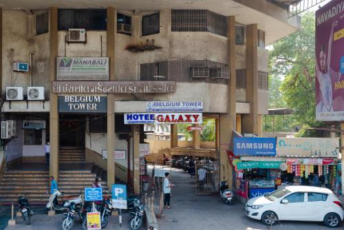 a city street with a building with cars and motorcycles at Hotel Galaxy Opp Surat Railway Station in Surat