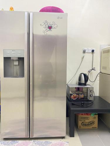 a stainless steel refrigerator in a kitchen next to a table at Homestay Zalida D Musleem in Kampong Alor Gajah