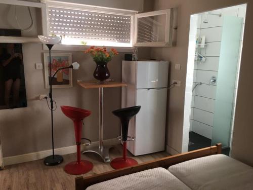 a living room with a refrigerator and two red stools at Bialik St B&B room Bauhaus district Tel Aviv in Tel Aviv