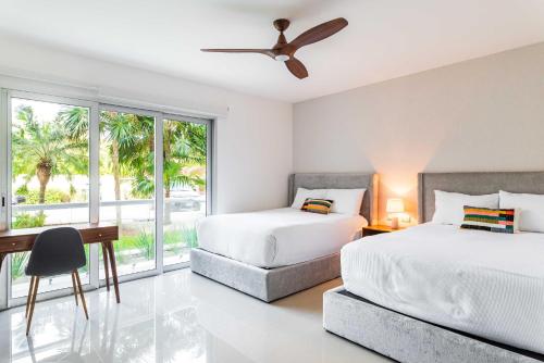 a bedroom with two beds and a desk and a window at Mareazul Beach Front Condos At playa del Carmen in Playa del Carmen