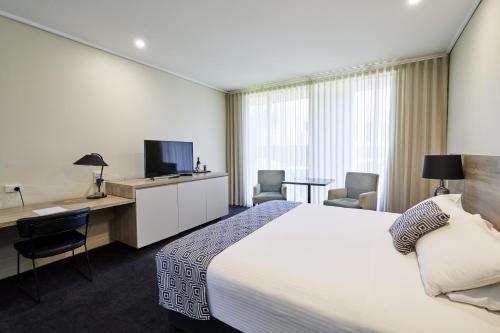a hotel room with a bed and a desk and a tv at The Dingley Hotel in Dingley