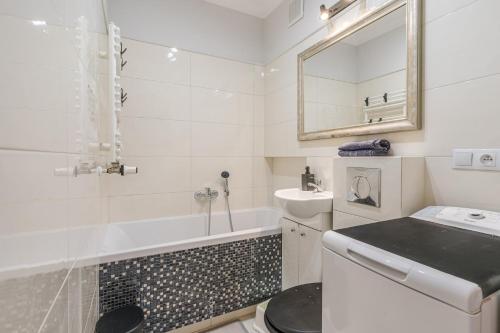 a white bathroom with a tub and a sink at Black Chairs - Apartament blisko morza in Gdańsk