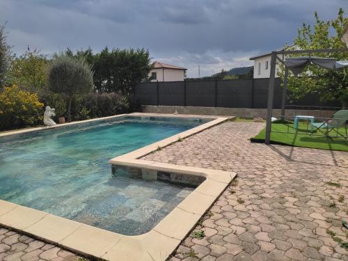 - une piscine dans un jardin avec une table et un parasol dans l'établissement Le Temps Retrouvé, à Saint-Martin-de-Valgalgues