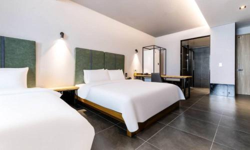 a hotel room with two beds and a desk at Anseong Nomad Hotel in Anseong