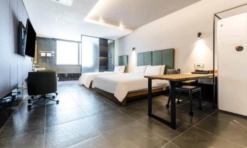a hotel room with a bed and a desk and a table at Anseong Nomad Hotel in Anseong