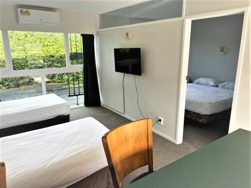 a hotel room with two beds and a tv at Ranfurly Evergreen Motel in Auckland